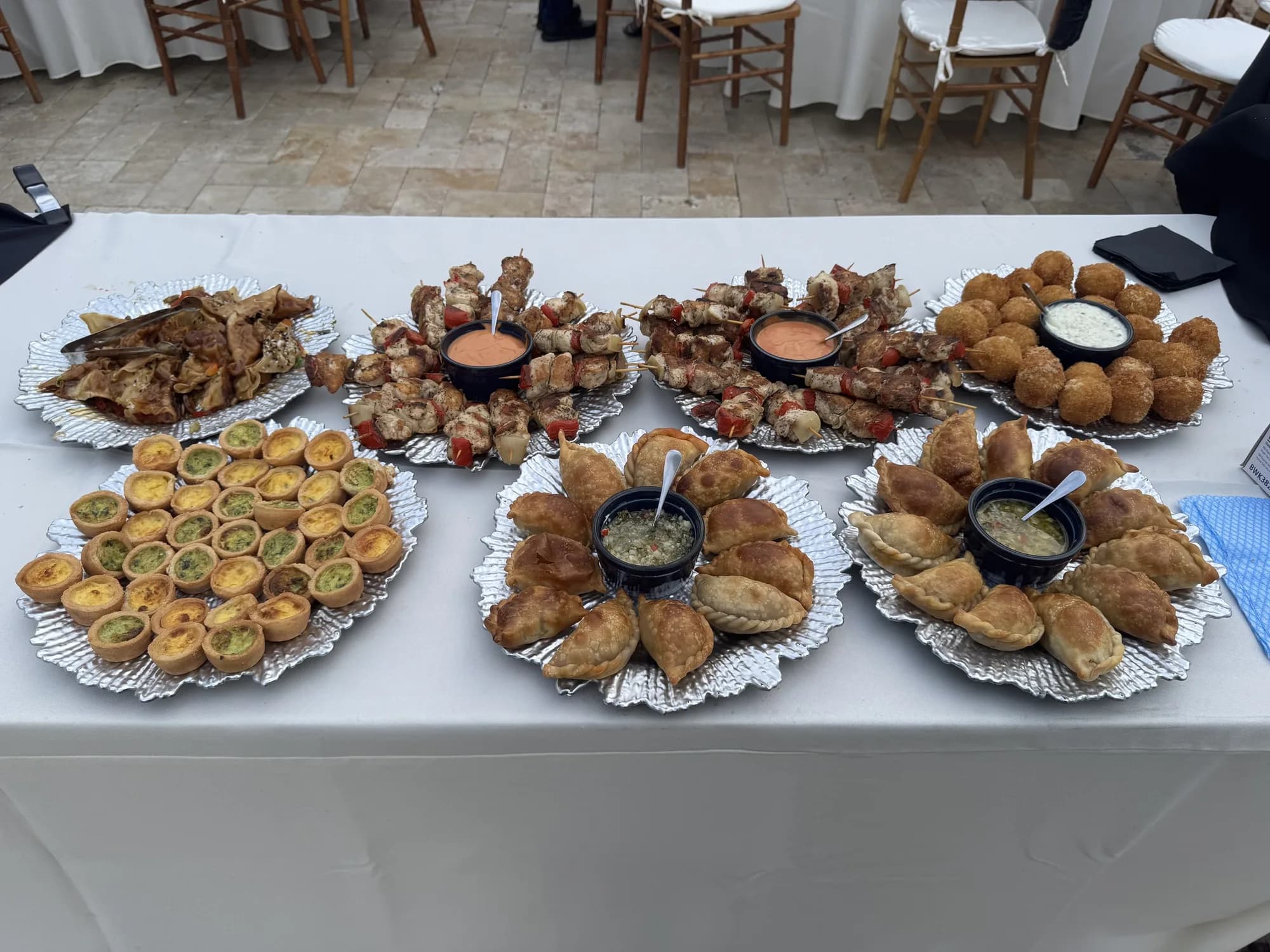 Assorted appetizer platters on a white catering table