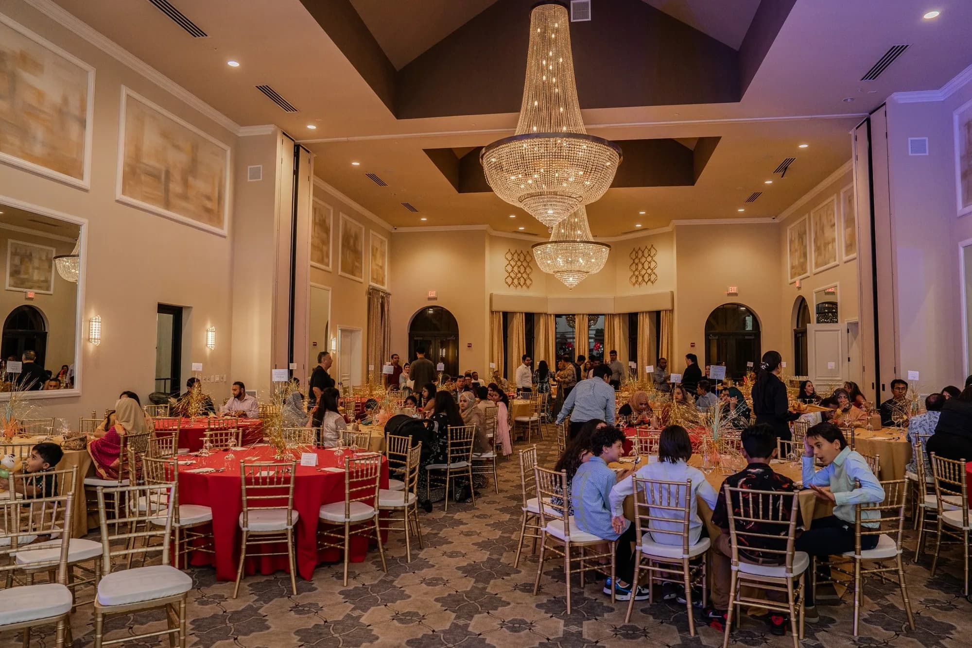 Ballroom with red linens set for a birthday dinner