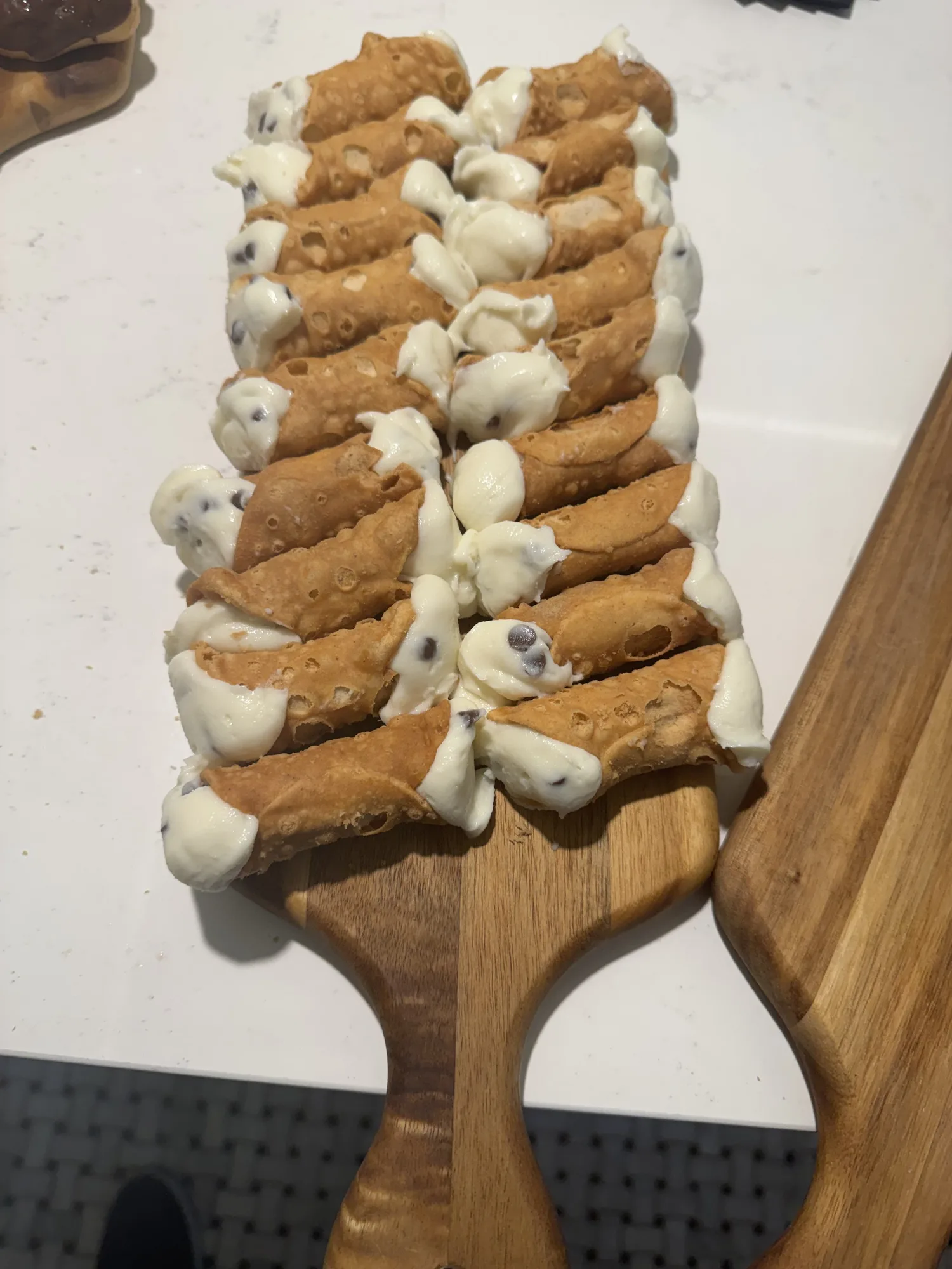 Cannoli lined up on a wooden serving board