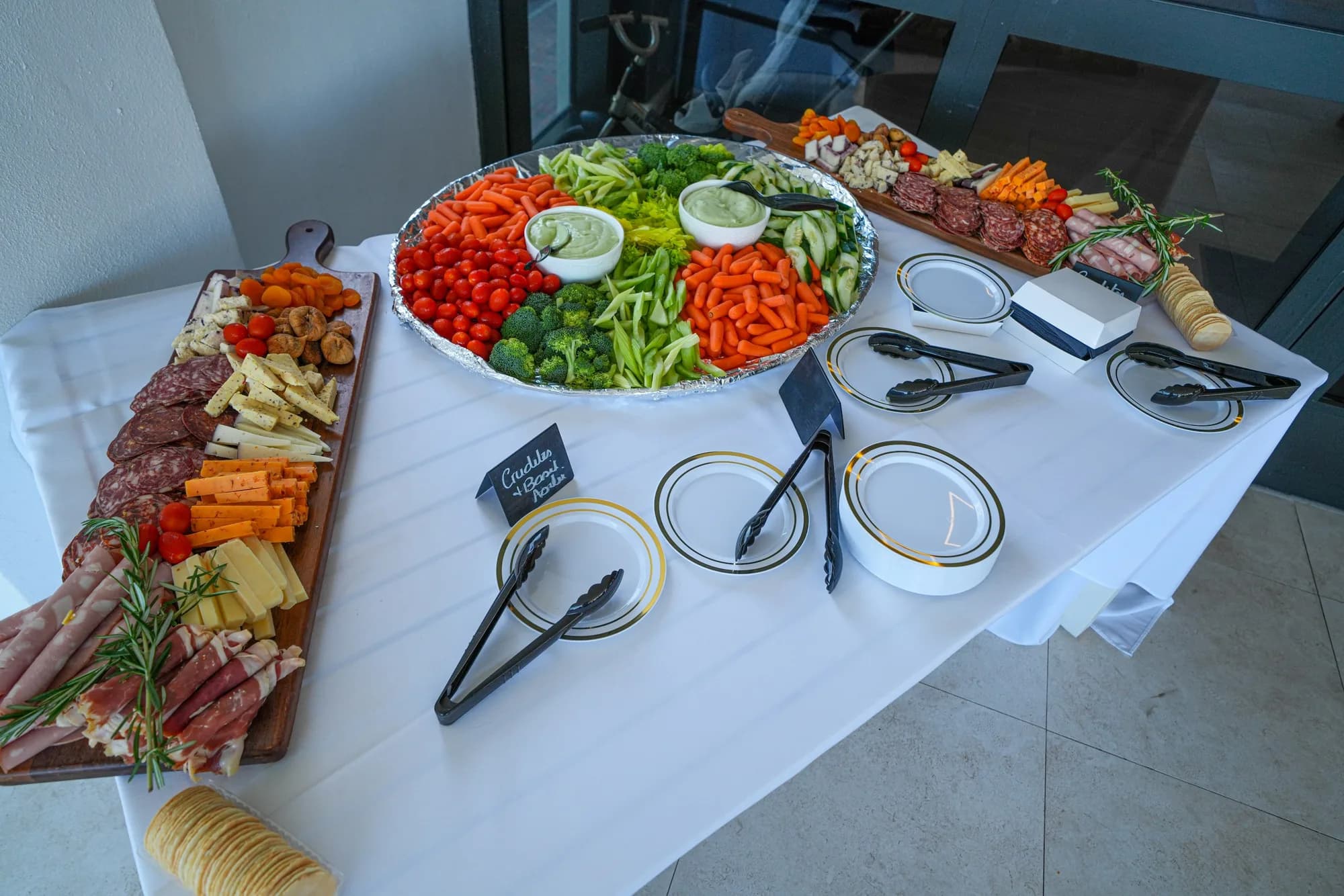 Crudité and charcuterie platter with dips on a linen-covered catering table