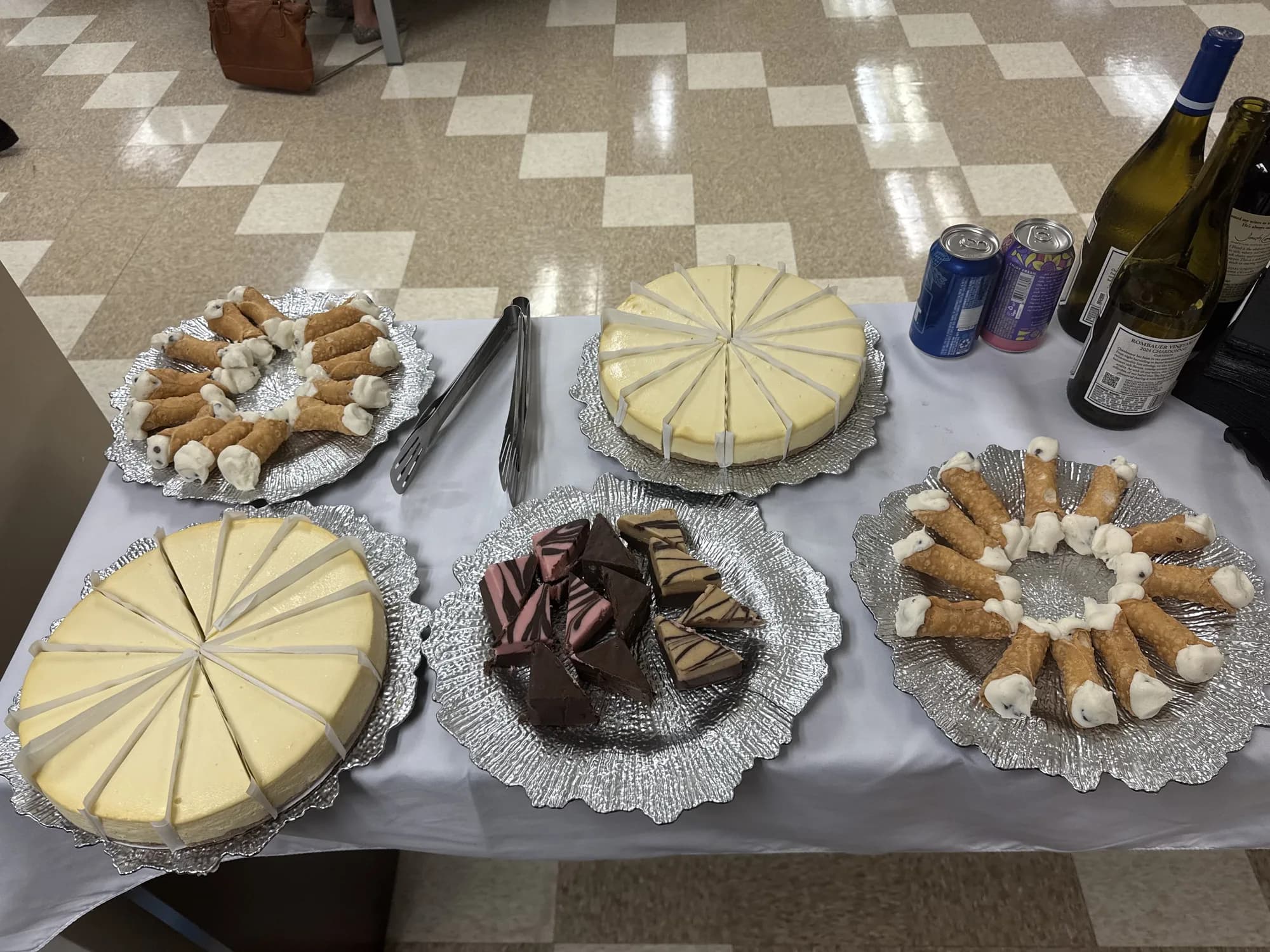Dessert table with cakes, cannoli and wine at a catered party