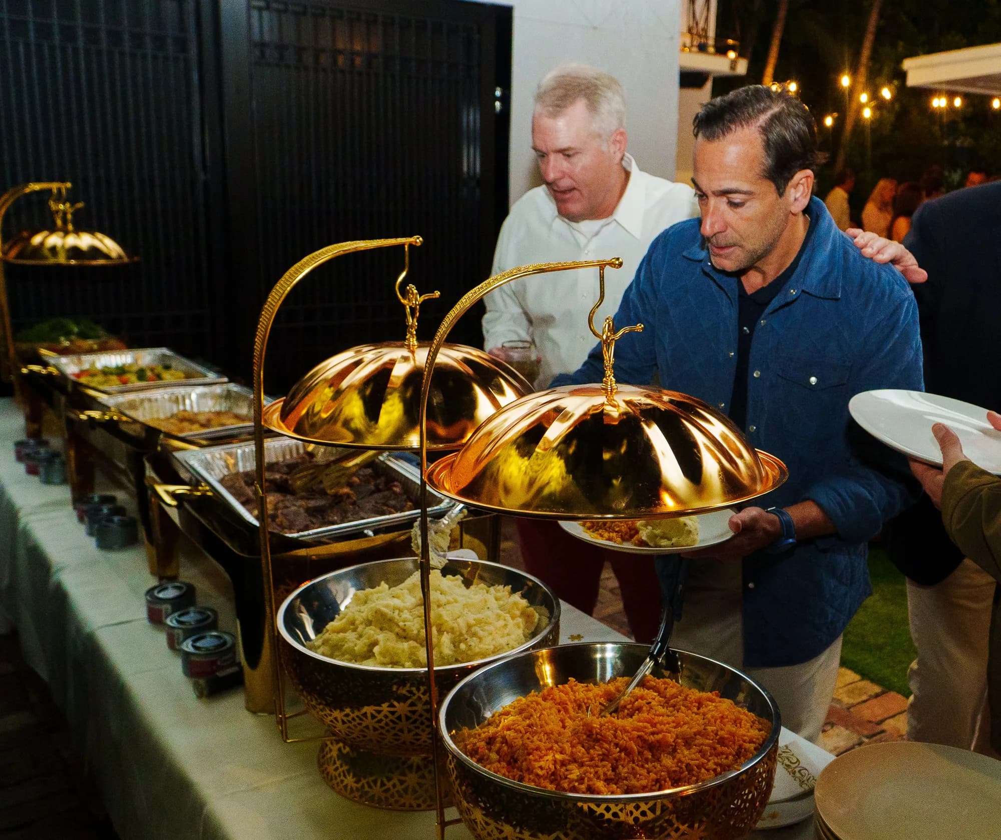 Gold chafing dishes at an outdoor evening buffet