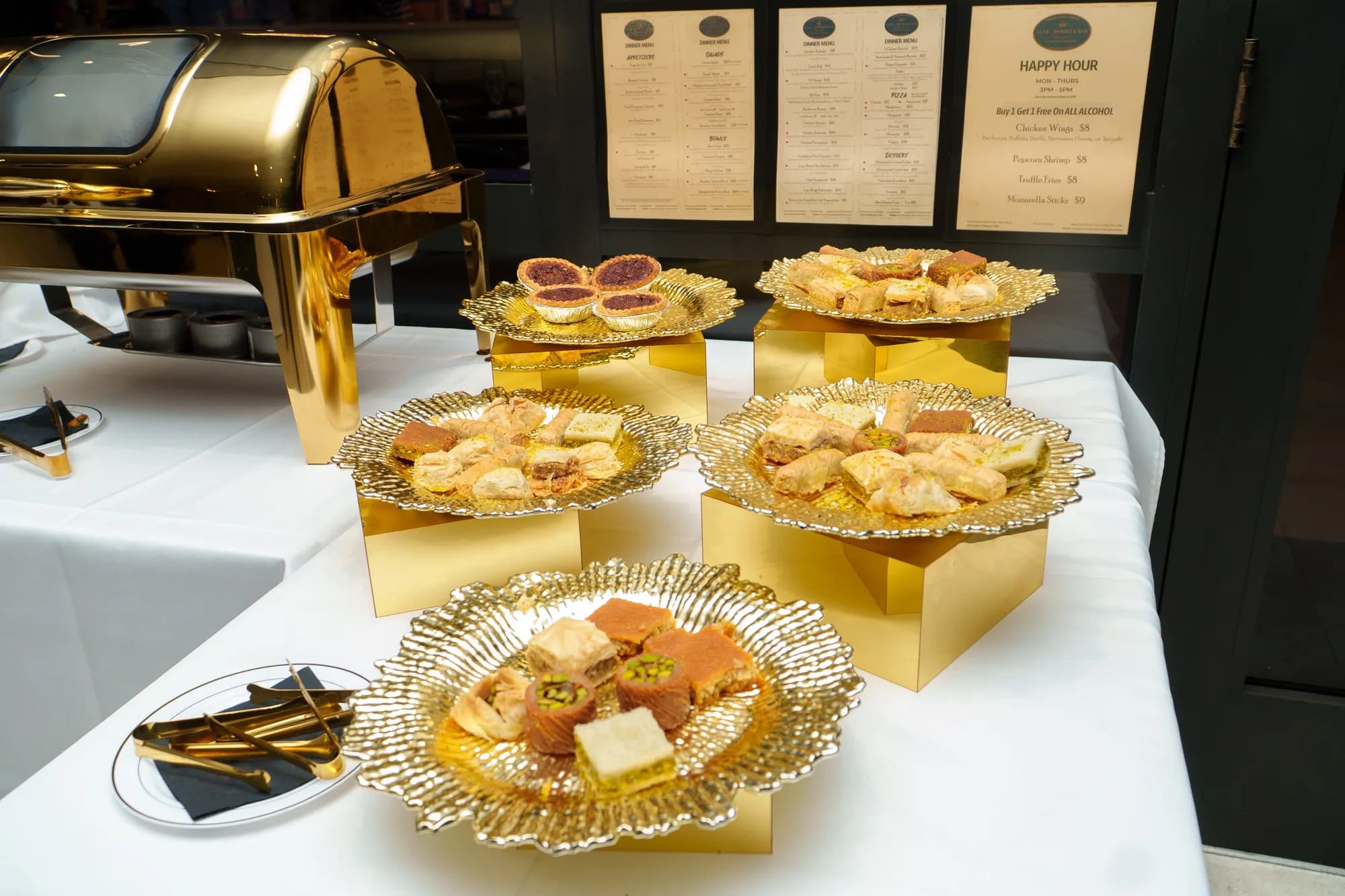 Gold-trimmed appetizer platters on a white catering table