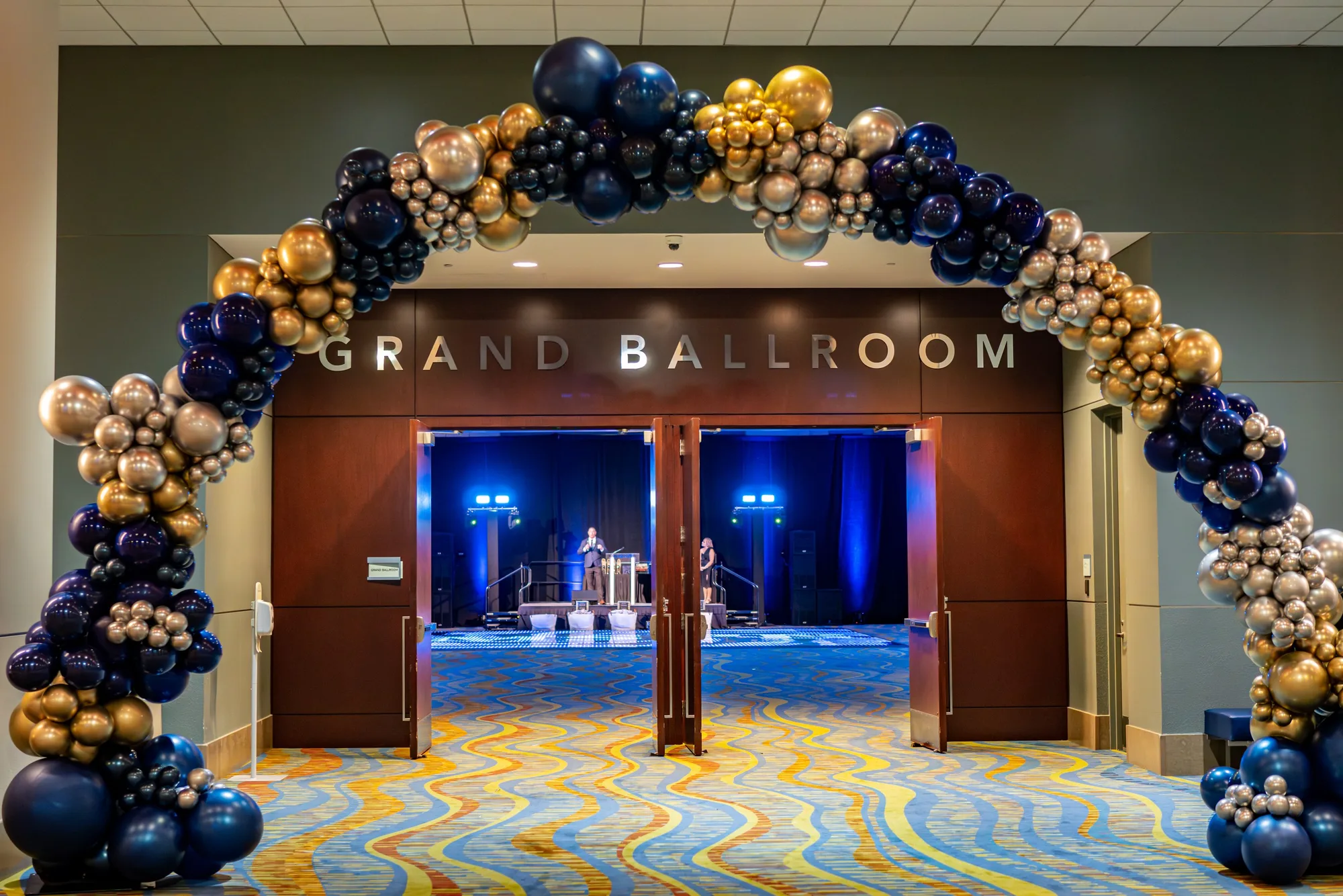 Grand ballroom entrance with navy and gold balloon garland