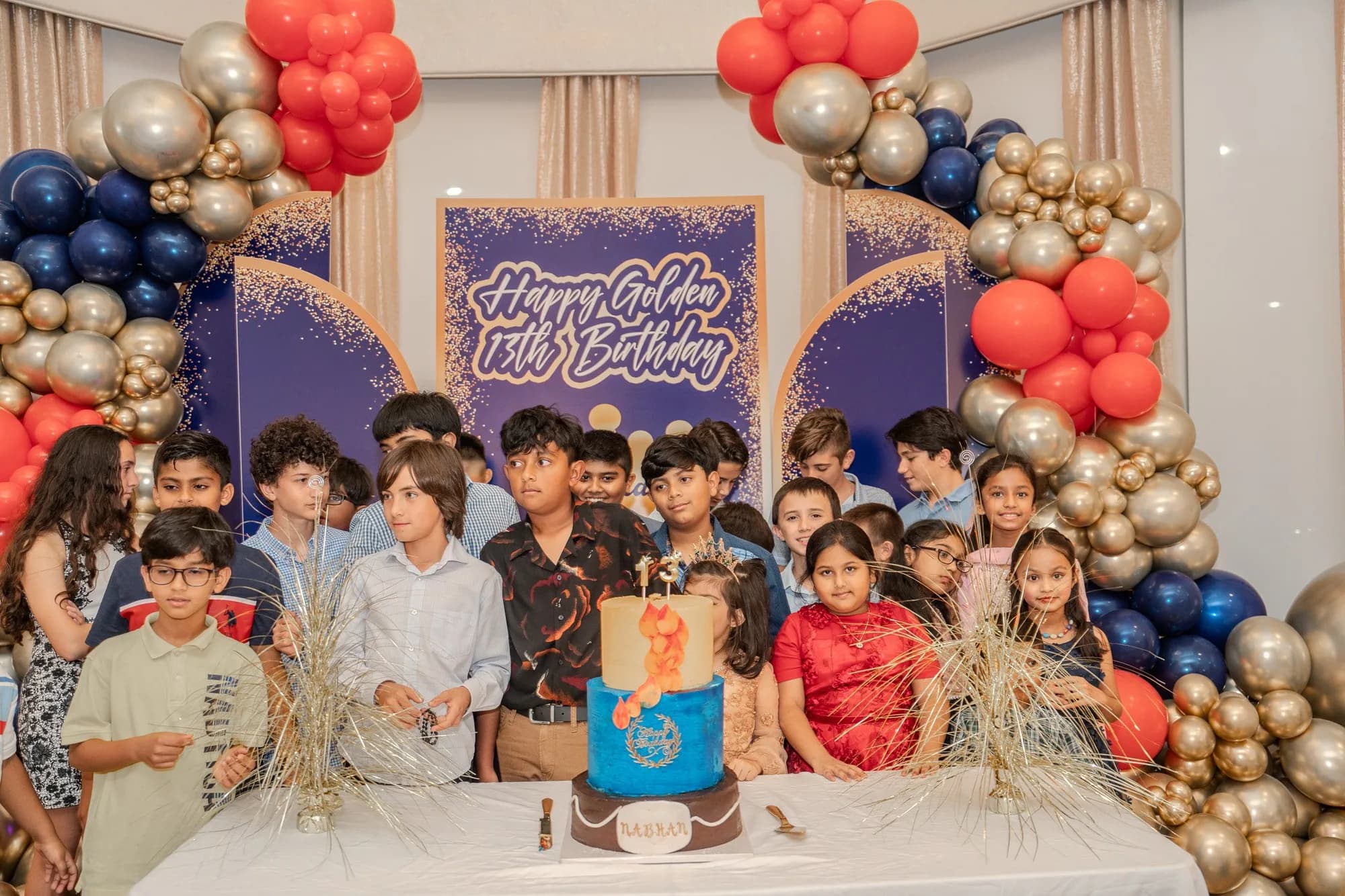 Children with the birthday cake at a balloon arch