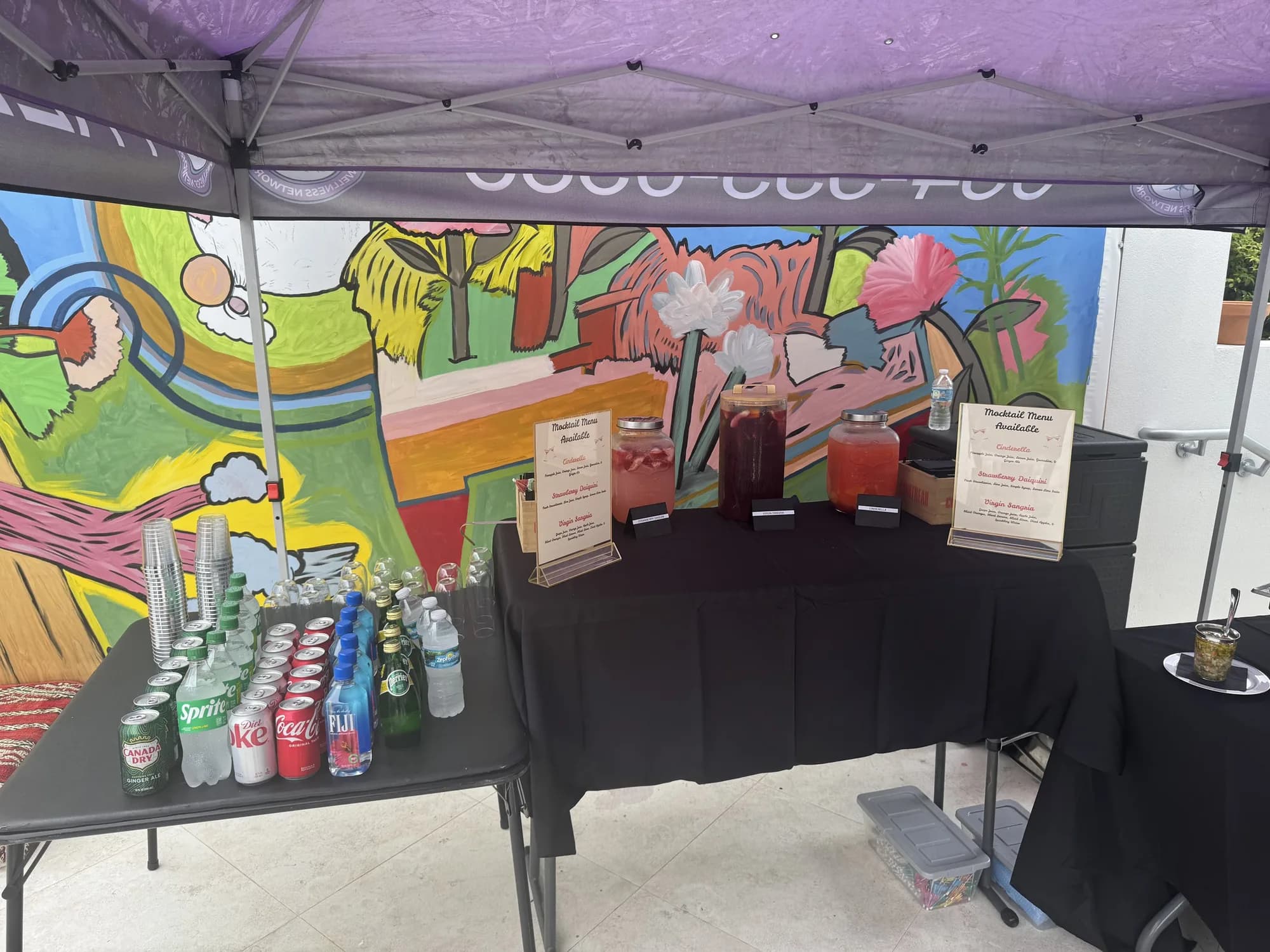 Catering tent beside a mural at an outdoor community event