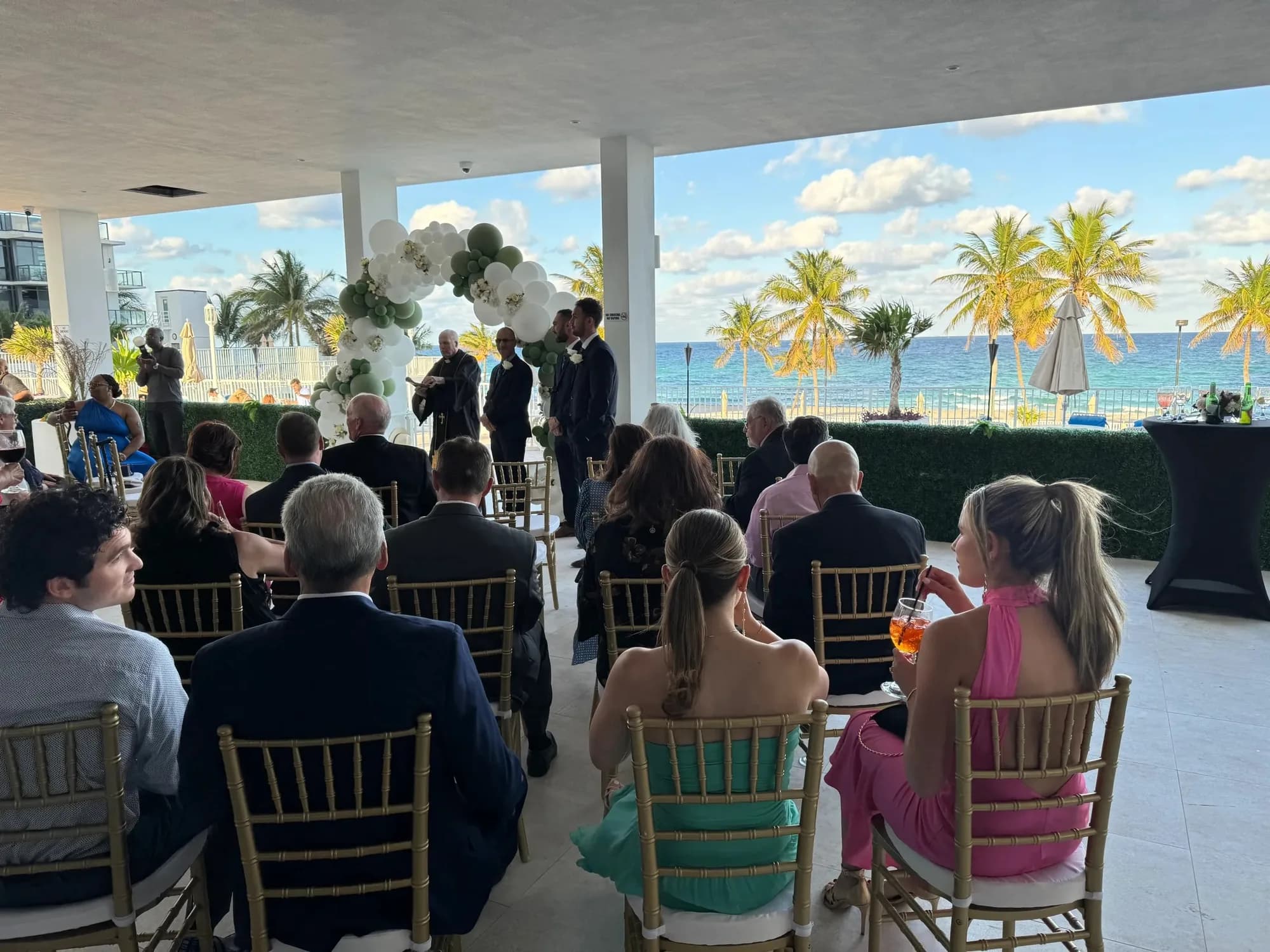 Guests seated for an oceanfront ceremony with palm trees