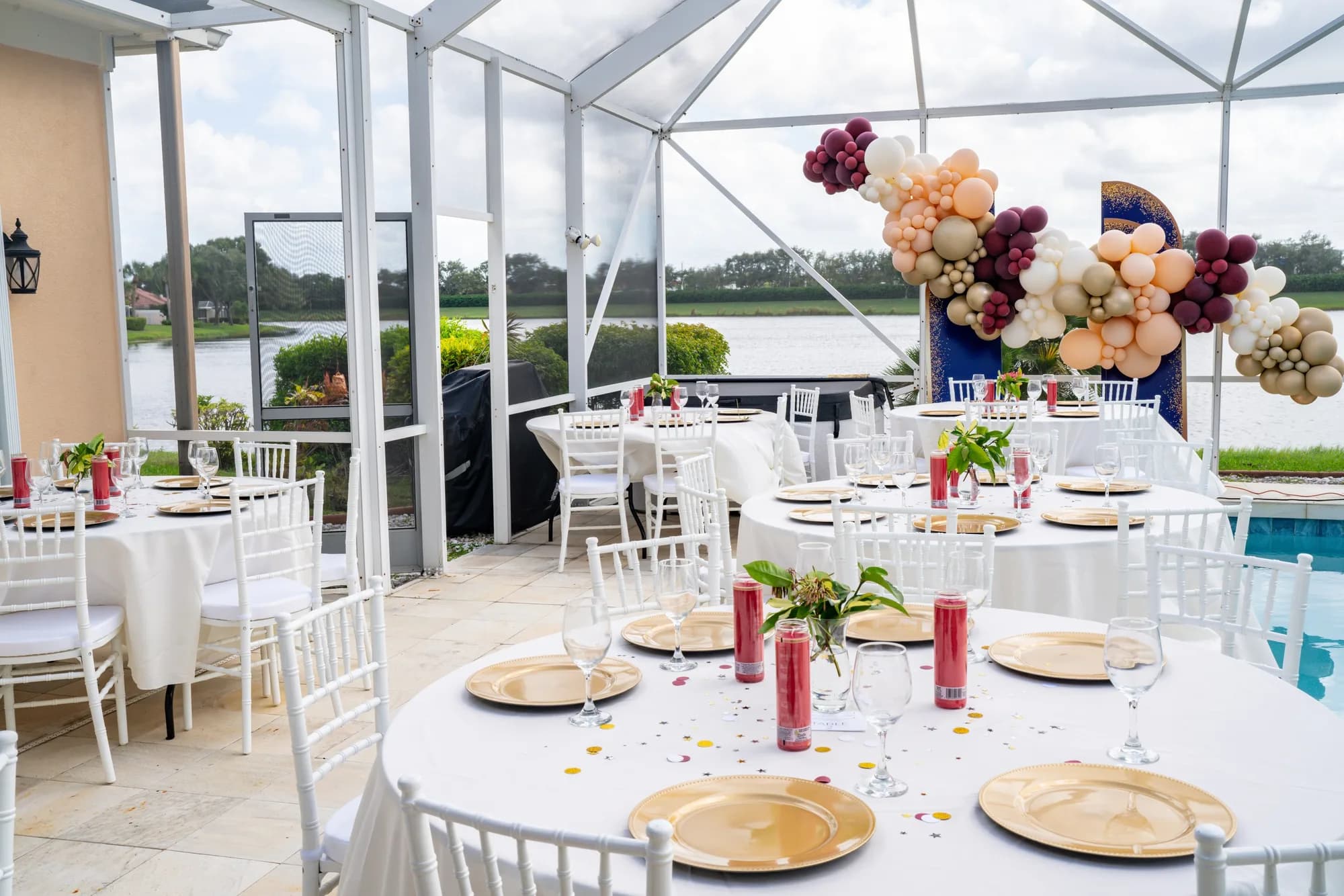 Poolside wedding reception with balloon garland and gold chargers