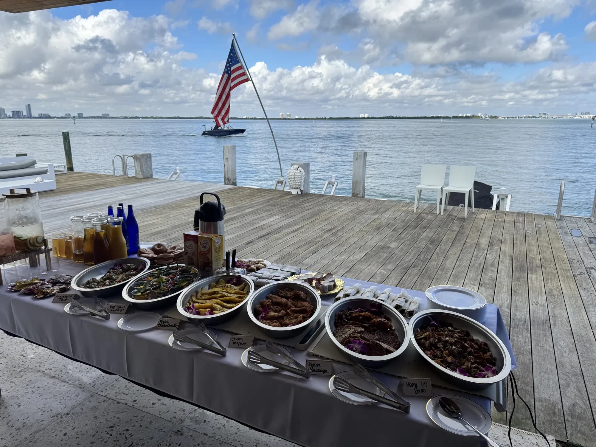 Catered buffet set up on a waterfront dock with the bay behind it
